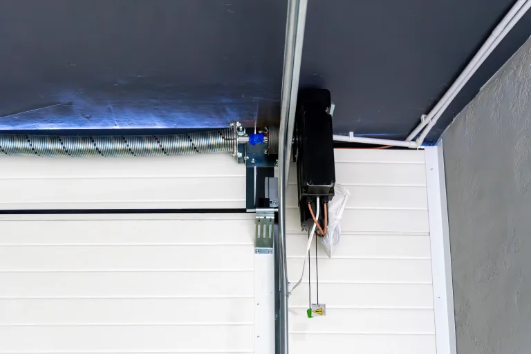 Wall-mounted electric opener beside a white sectional garage door