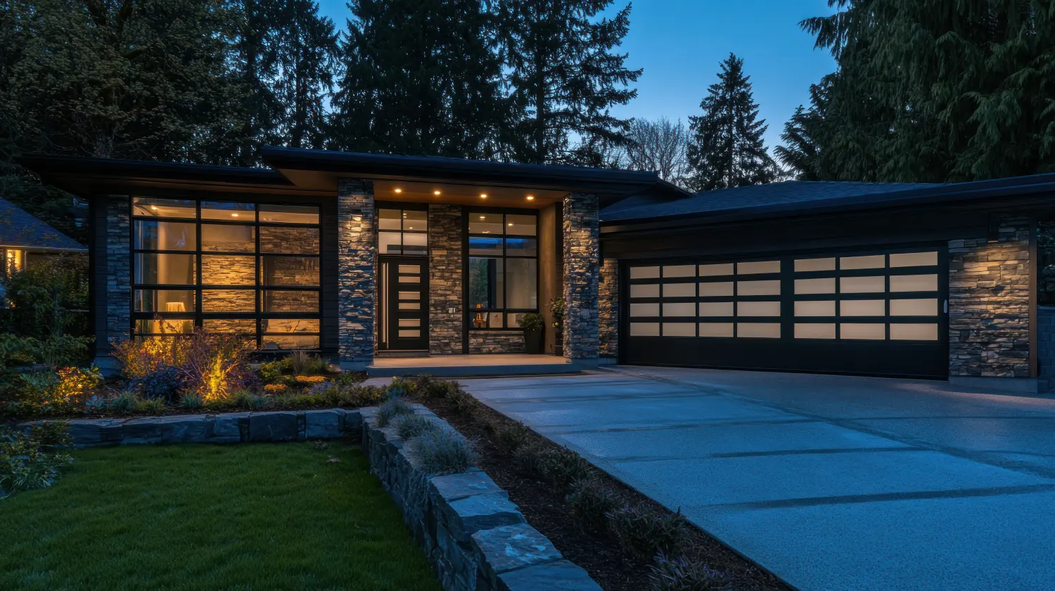 Modern home with a lit glass garage door at dusk