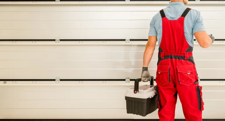 Garage door installer with a toolbox in front of a new sectional door