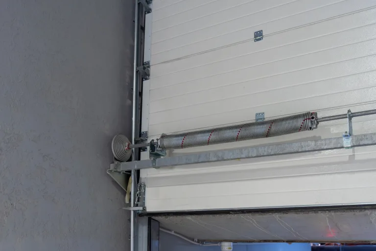Torsion spring and electric opener mounted above a white sectional garage door