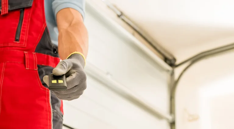 Installer holding a garage door remote control after finishing a new door